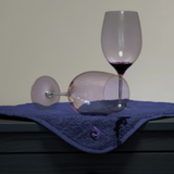 two wine glasses on navy sex mat. One wine glass has spilled over and is absorbed by mat